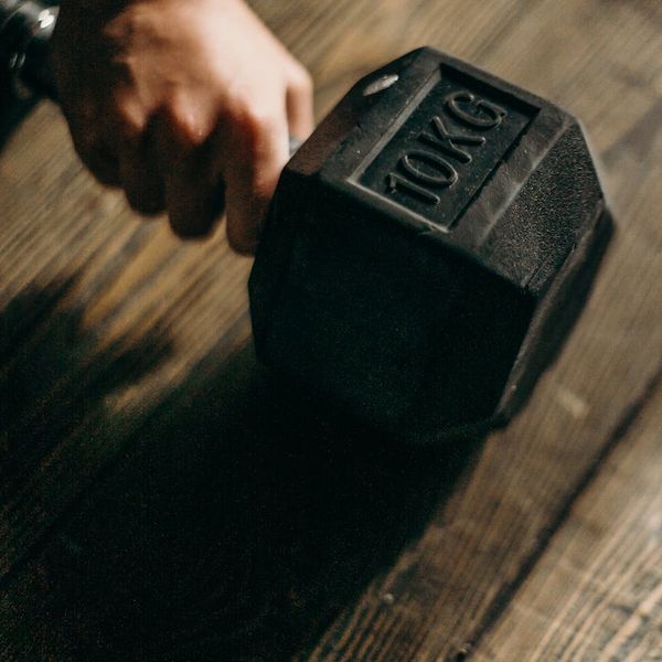 Man hands gripping a heavy metal dumbbell during training